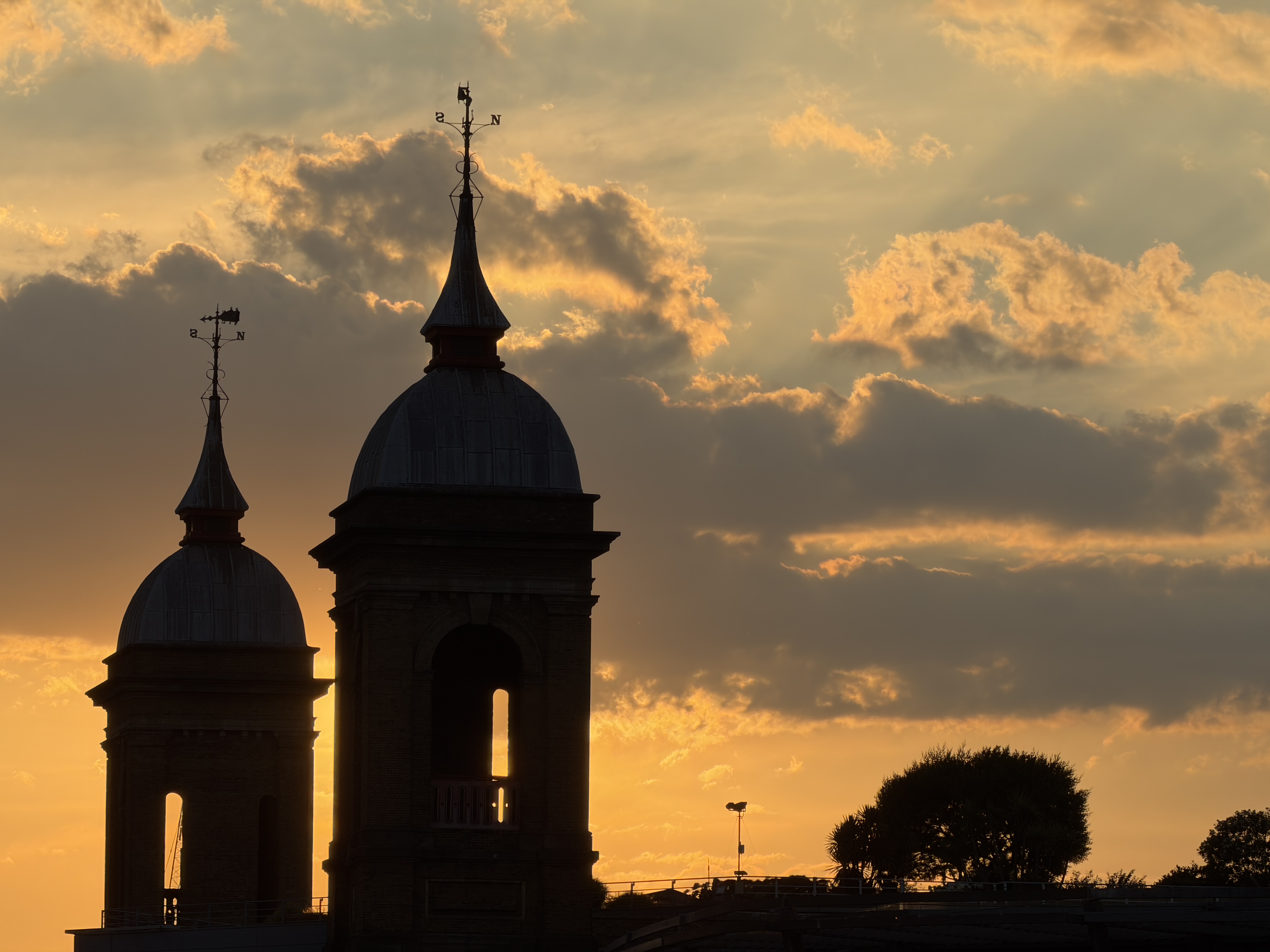 Two silhouetted towers beneath golden clouds at sunset.